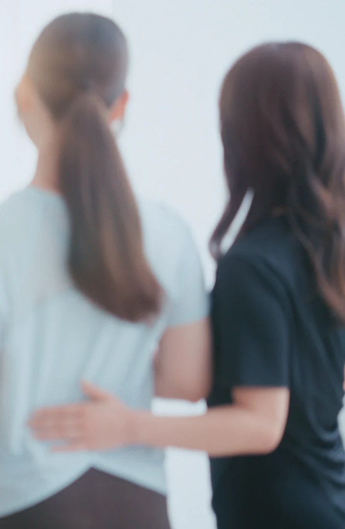 トレーナーが背中に手を添えて姿勢を確かめている様子