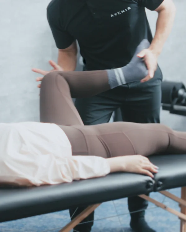 トレーナーがお客様の脚を支えて、ていねいに伸ばしている様子