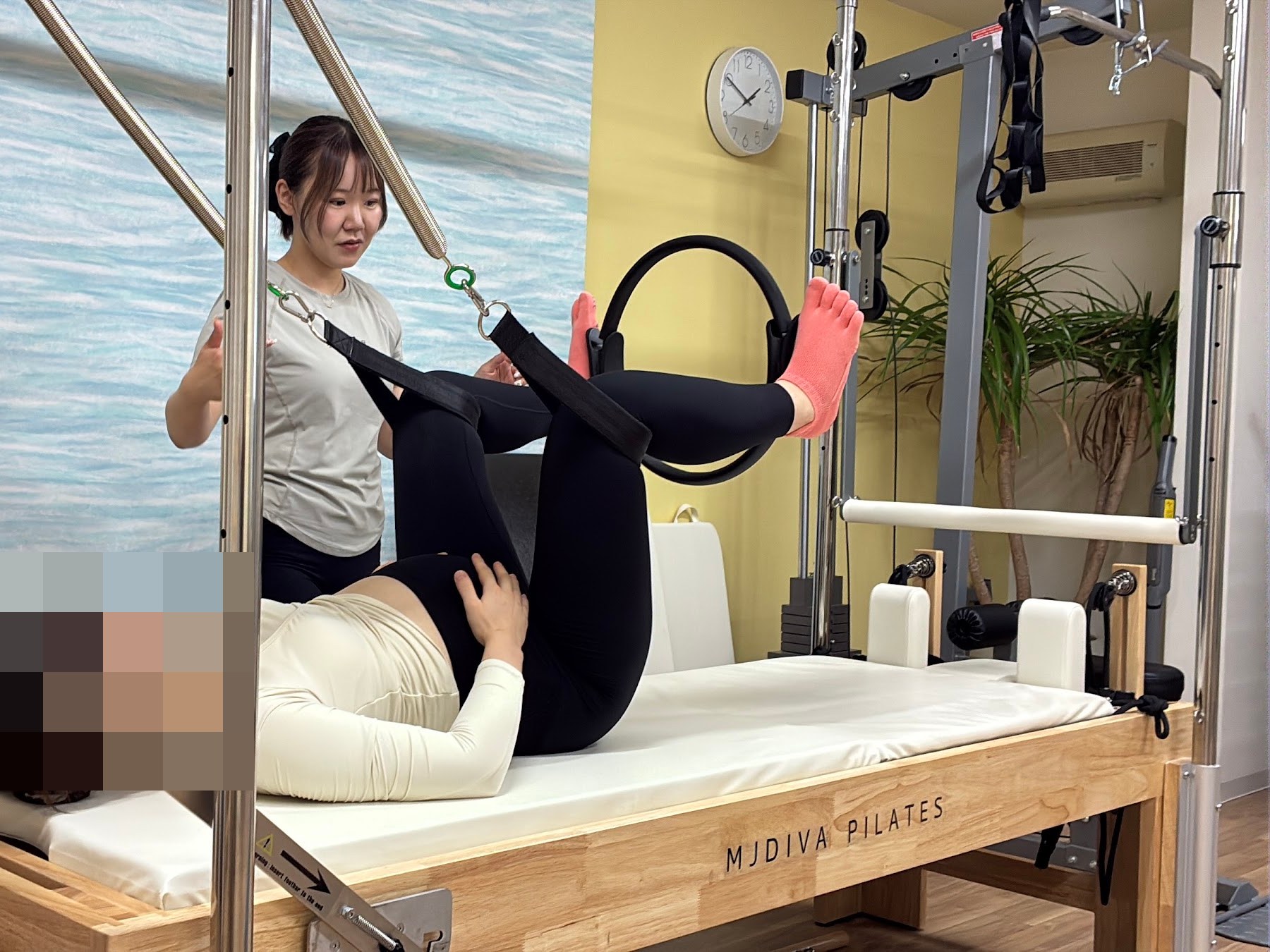 マタニティピラティス：トレーナーの補助で、マシンを使って体を伸ばす妊娠中の方